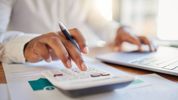 Person using a calculator and laptop, likely dealing with financial aspects related to company fines in the UAE.