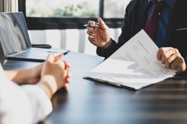 Business meeting discussing restricted activities, with documents and a pen pointing at prohibited business actions in Dubai.