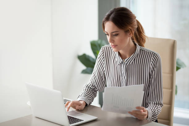 Businesswoman reviews documents at a desk, representing business compliance with regulations in Dubai and UAE.