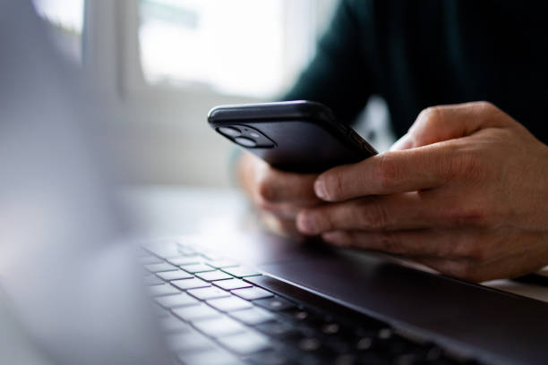 Person using a smartphone next to a laptop, representing digital communication for businesses in Dubai and the UAE.