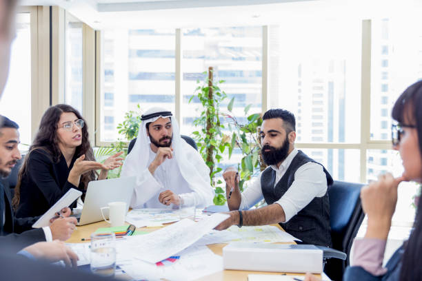 Business professionals discuss strategy in a modern office, highlighting collaboration in KIZAD Free Zone planning.