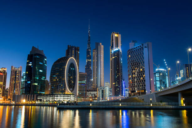 Night view of modern illuminated buildings reflecting on water, highlighting vibrant business opportunities.