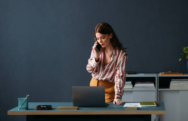 A businesswoman in an office setting discusses company name requirements in the UAE on her phone.